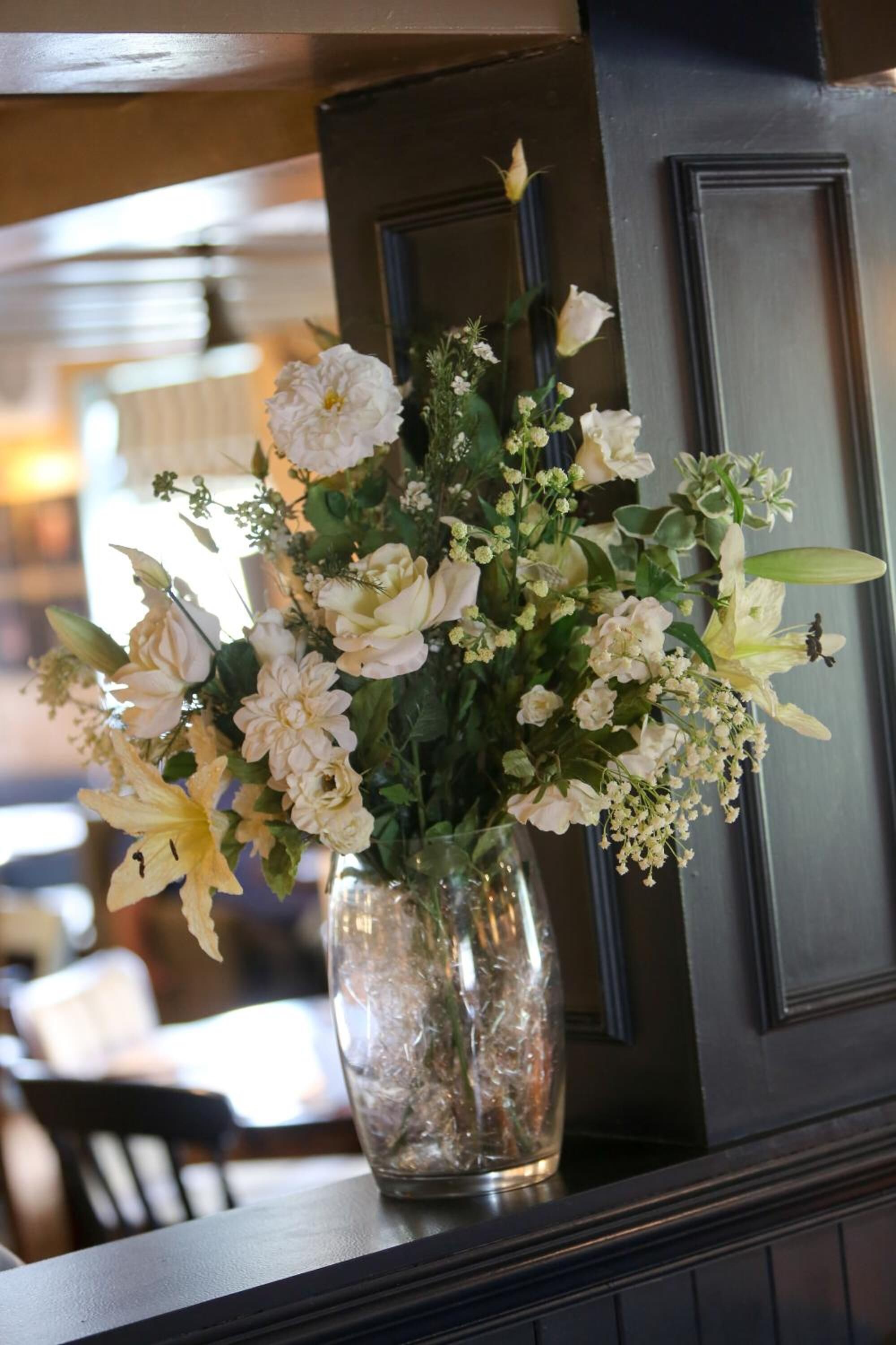 A vase of flowers on a table in a room with wooden paneling and a door.