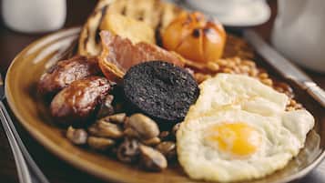 A breakfast plate with sausages, black pudding, fried eggs, mushrooms, and toast.