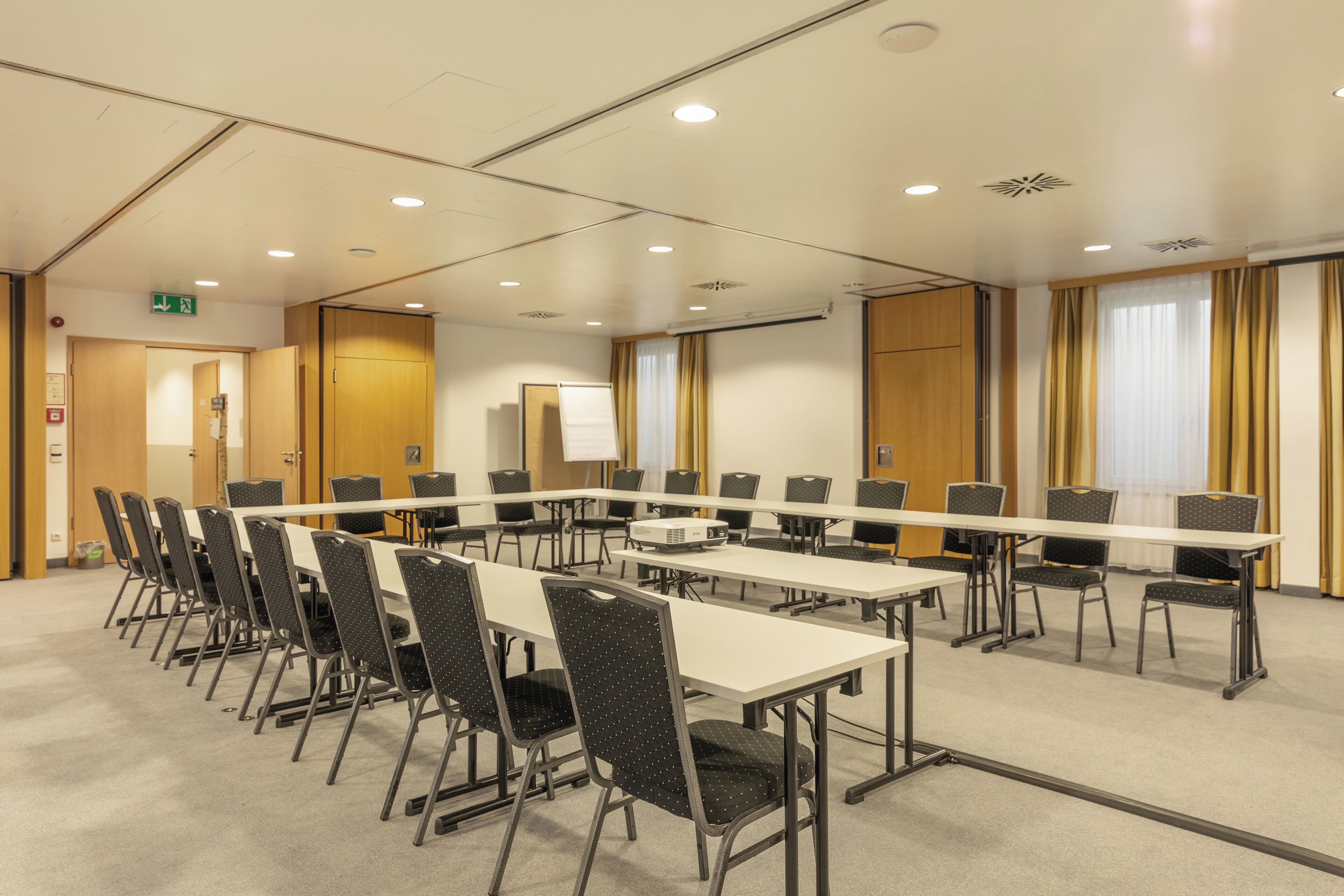 Une salle de conférence équipée d’une longue table et de chaises, d’un projecteur et d’un tableau blanc.