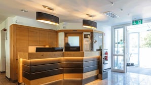 A reception area with a wooden counter and bench seating, a fire extinguisher, and a glass door leading outside. - MEAT & STAY HOTEL (Haar)