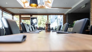 A conference room with a long table, chairs, and a television screen. - MEAT & STAY HOTEL (Haar)
