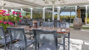 An outdoor dining area with tables and chairs, a wooden barrel, and a flower arrangement. - MEAT & STAY HOTEL (Haar)