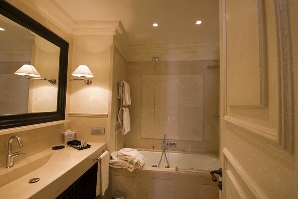 A bathroom with a sink, mirror, towel rack, and a shower area.