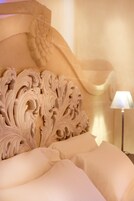 Una cama con cabecera decorada y una lámpara sobre la mesita de noche.
