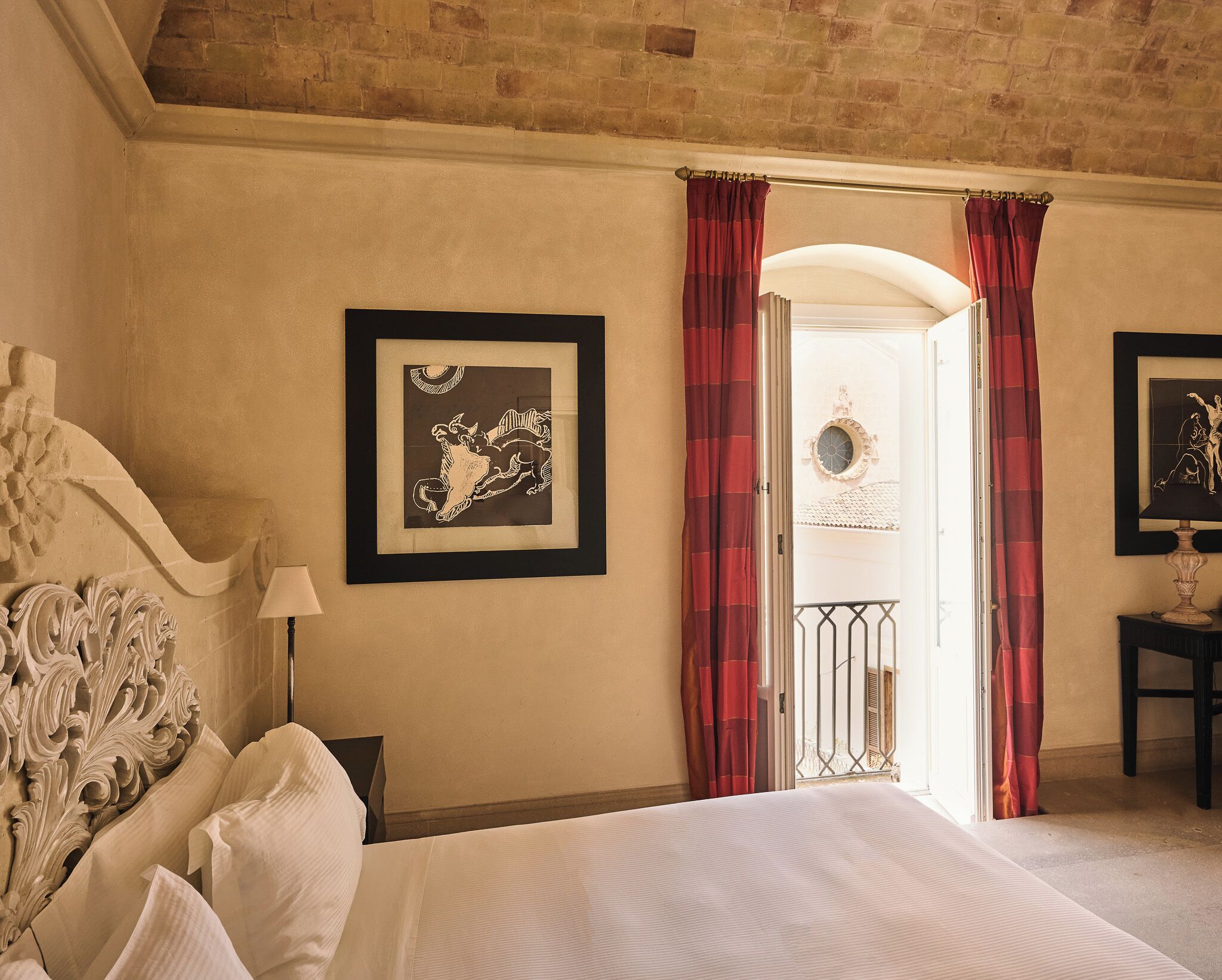 Une chambre d’hôtel avec un lit, une tête de lit, un tableau encadré, une lampe et une vue sur l’extérieur.
