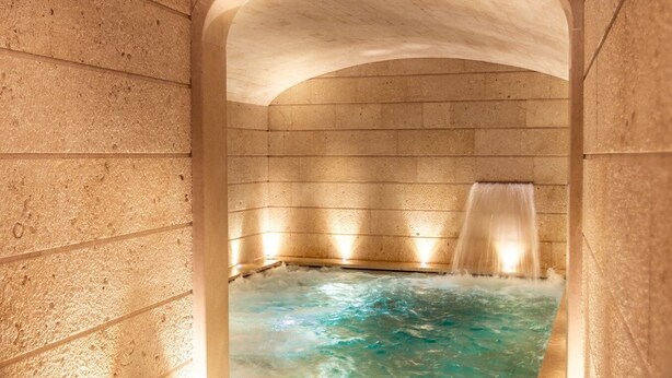 Un área de spa con un jacuzzi, paredes de piedra y piso de madera.