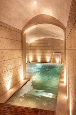 A spa area with a hot tub, stone walls, and a wooden floor.