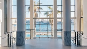 A spacious interior with large windows overlooking a pool and palm trees, featuring marble columns and a modern ceiling design. - Cavalieri Hotel Malta, a member of Radisson Individuals (St. Julian's)