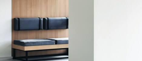 A minimalist room with a wooden panel wall, a low platform bed with black headboards, and a white floor.