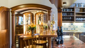 A bar area with a marble countertop, wine bottles, glasses, and a flower arrangement. - Romantik Hotel zur Post (Fuerstenfeldbruck)