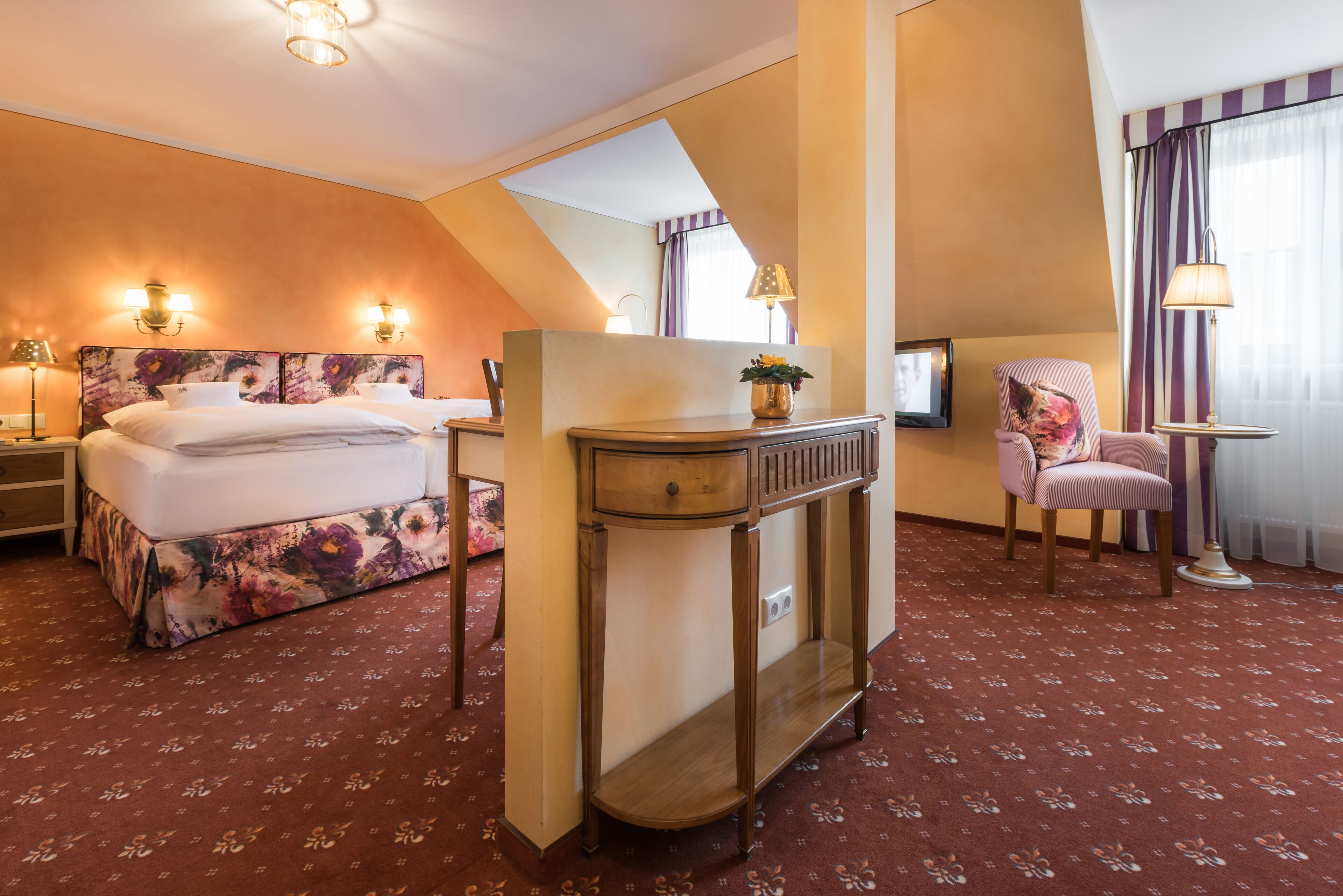 A hotel room with a bed, a desk, a chair, and a TV.