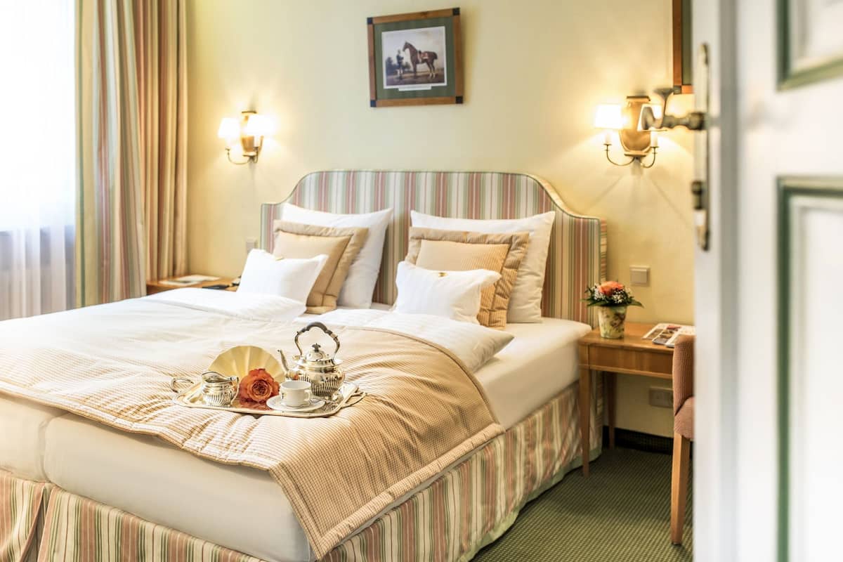 A neatly made bed with a striped headboard, a bedside table with a lamp, and a framed picture on the wall.