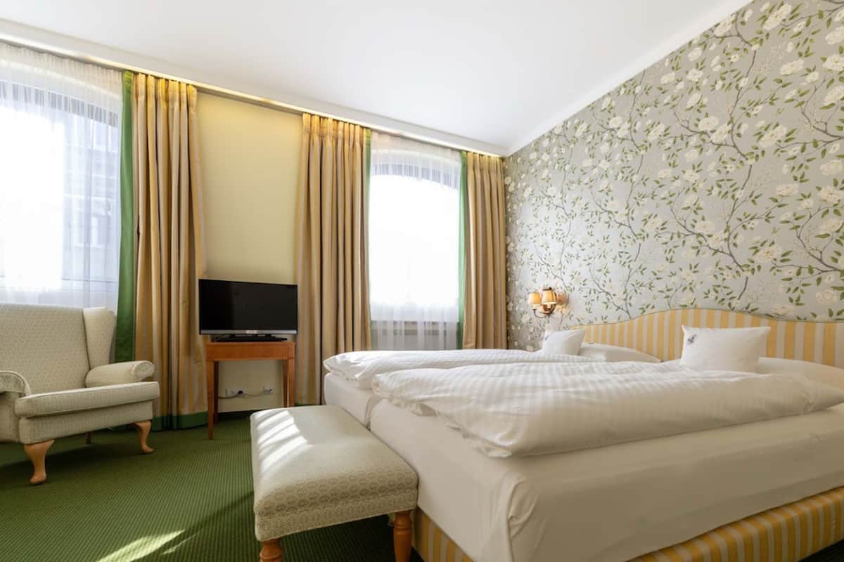 A hotel room with two beds, a TV, a chair, and a small table.