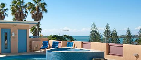 Piscina com hidromassagem, espreguiçadeiras e vista para o oceano.