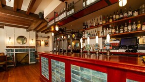 A bar with wooden floors, a red bar counter, and various liquor bottles on shelves. - The West Bay Hotel (Bridport)