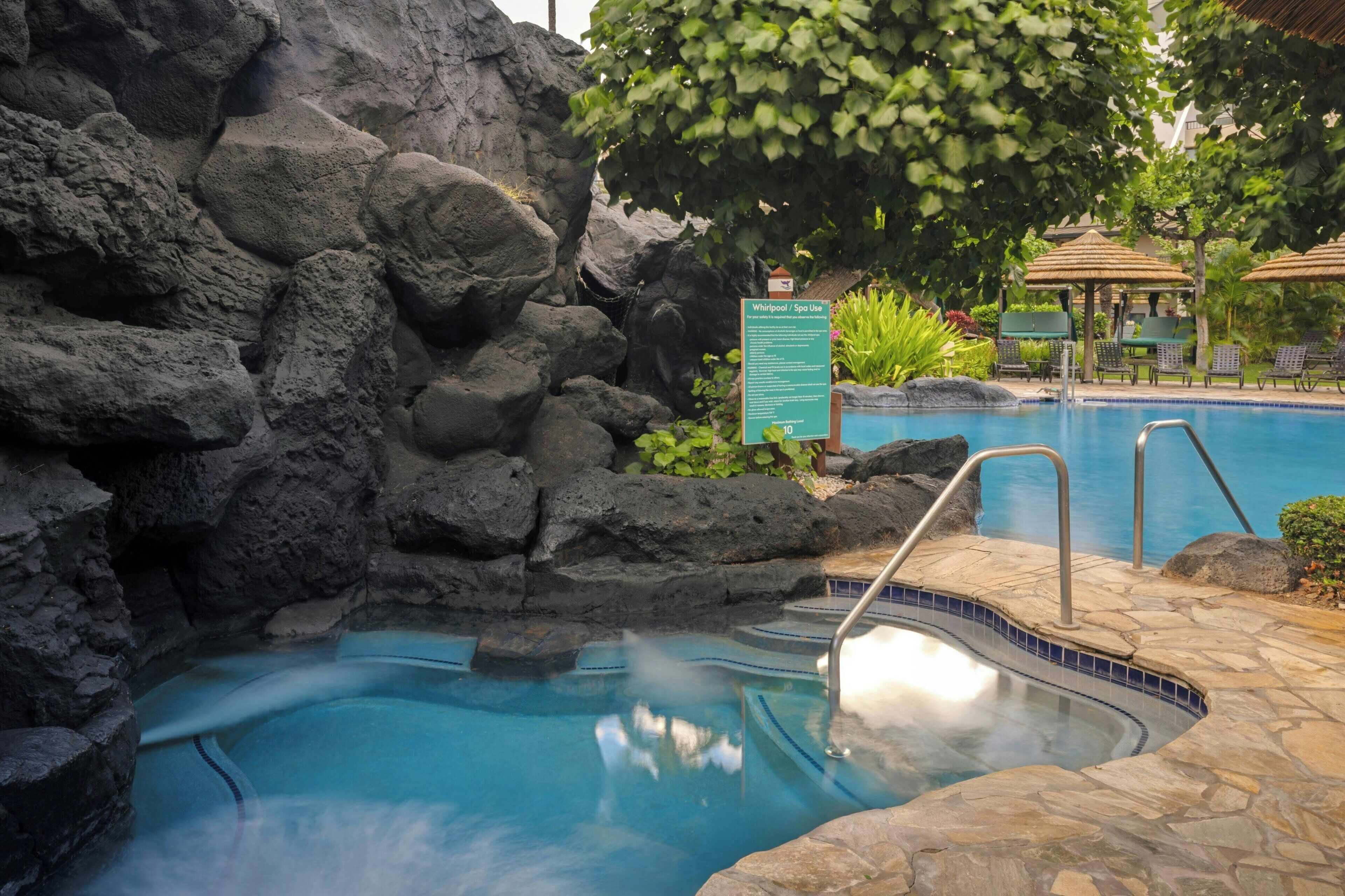 Une piscine avec un mur en pierre et un panneau indiquant qu’il s’agit d’un espace réservé aux bains à remous ou aux soins de spa.