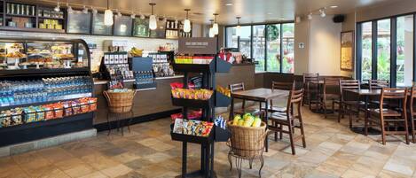 A coffee shop interior with a bakery display, seating area, and a sign reading "BEAR SOMETHING GOOD".