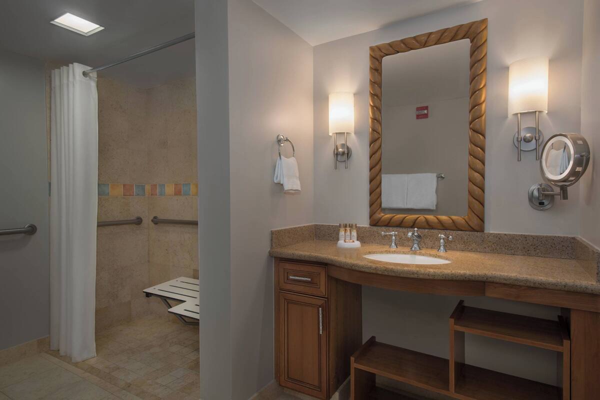 A modern bathroom with a shower, a vanity with a sink, and a large mirror.