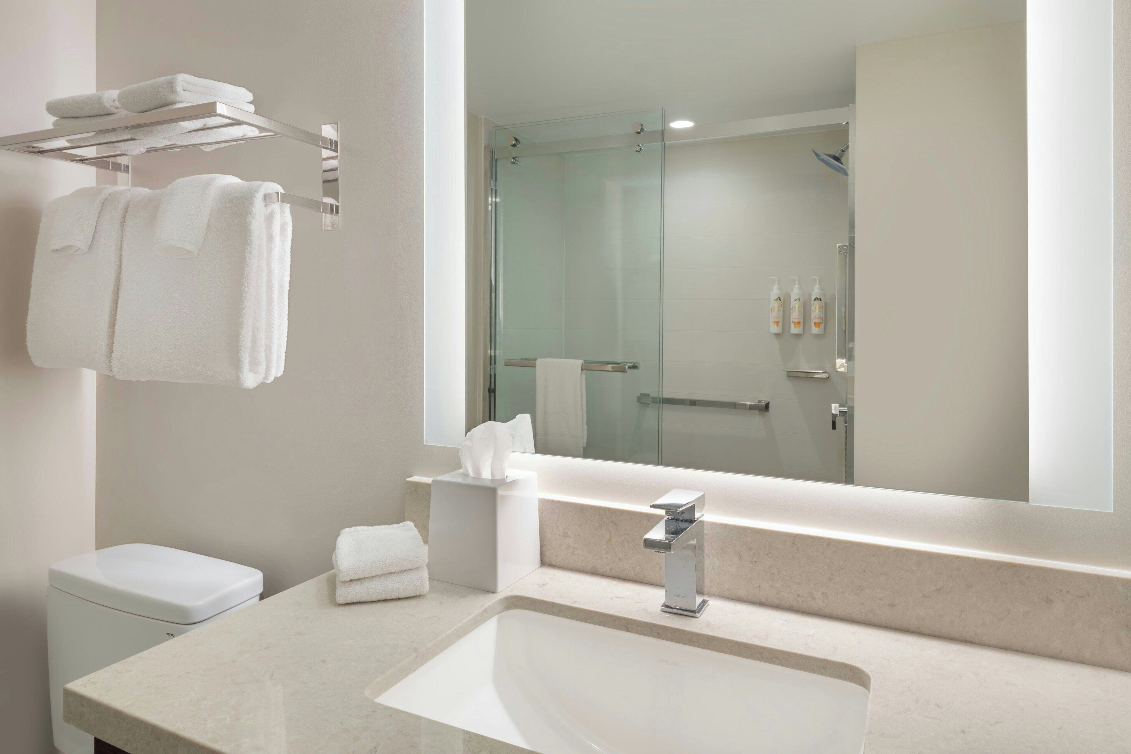 Un bagno moderno con uno specchio grande, un lavandino e una cabina doccia in vetro.
