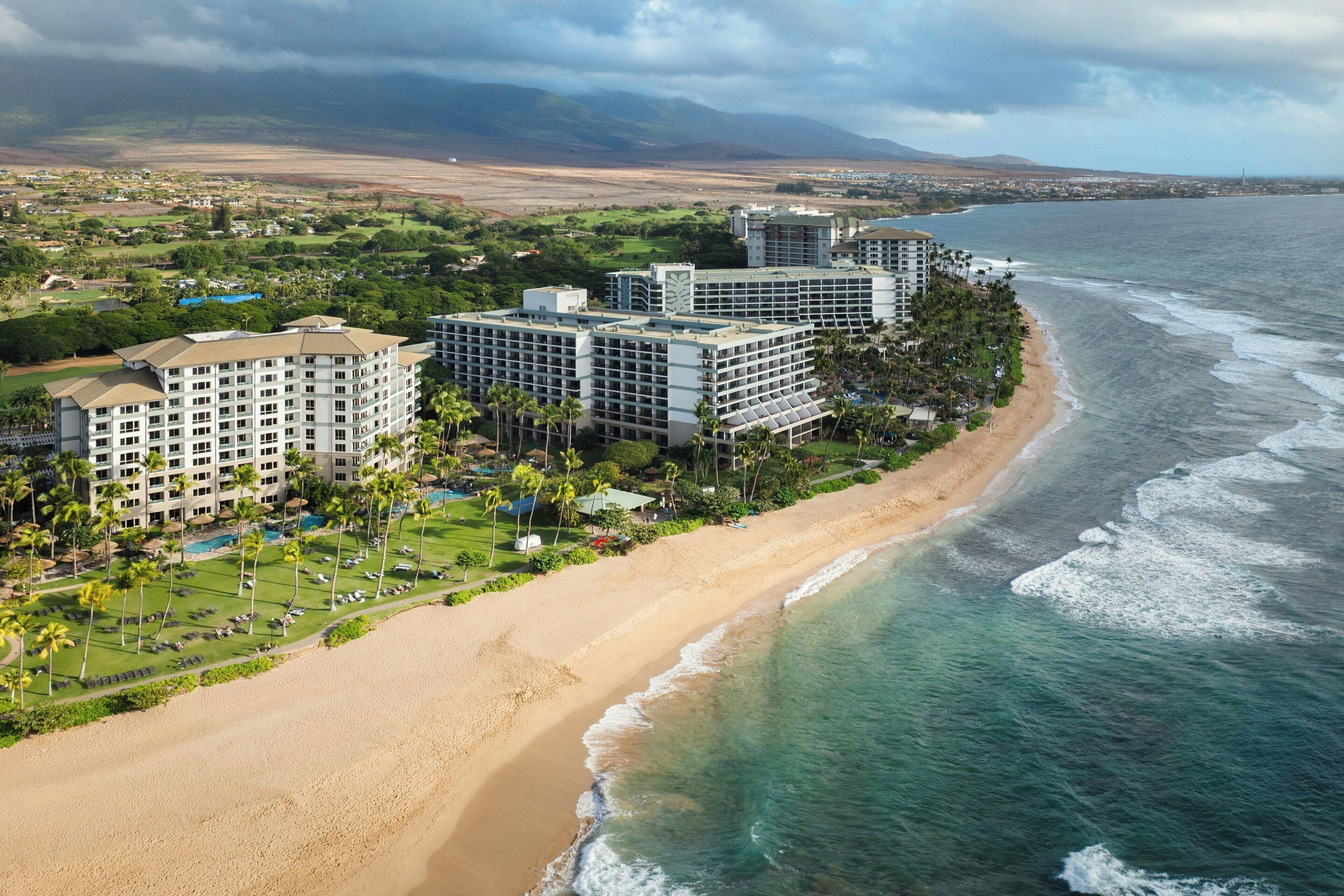 A coastal hotel with multiple buildings, a beach, and ocean views.