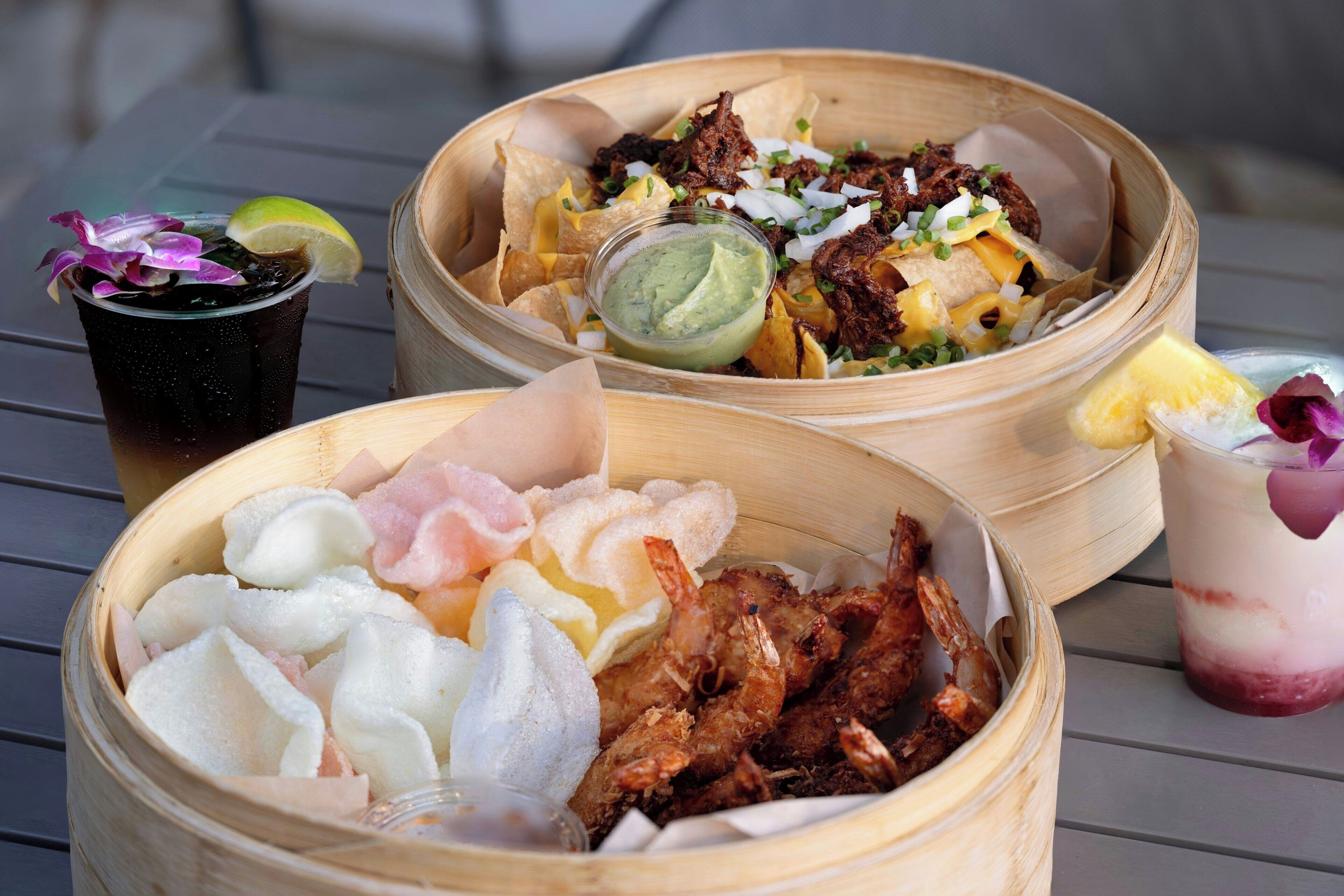 A table with three bamboo baskets containing food and drinks.