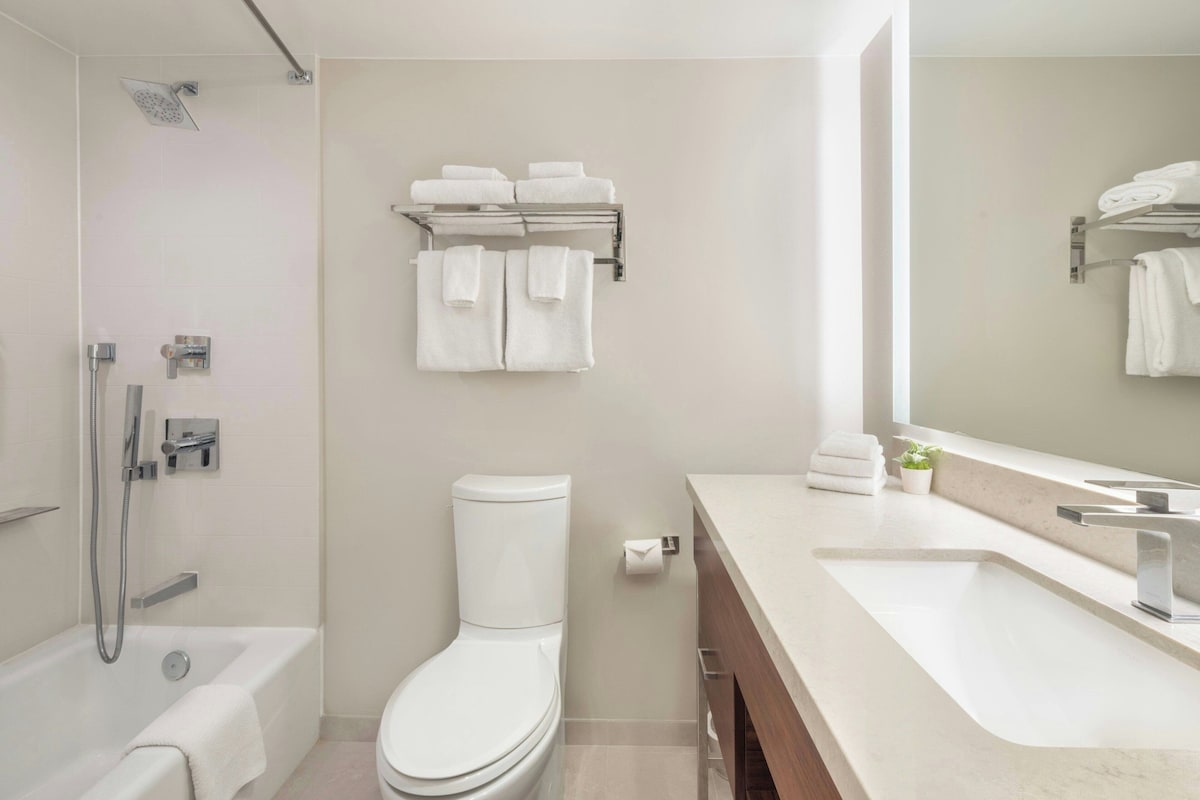 A modern bathroom with a bathtub, toilet, and a vanity with a sink.