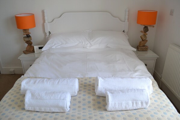 A neatly made bed with white linens, two bedside tables with orange lamps, and a polka dot bedspread. - Tregony Guest House (St Ives)