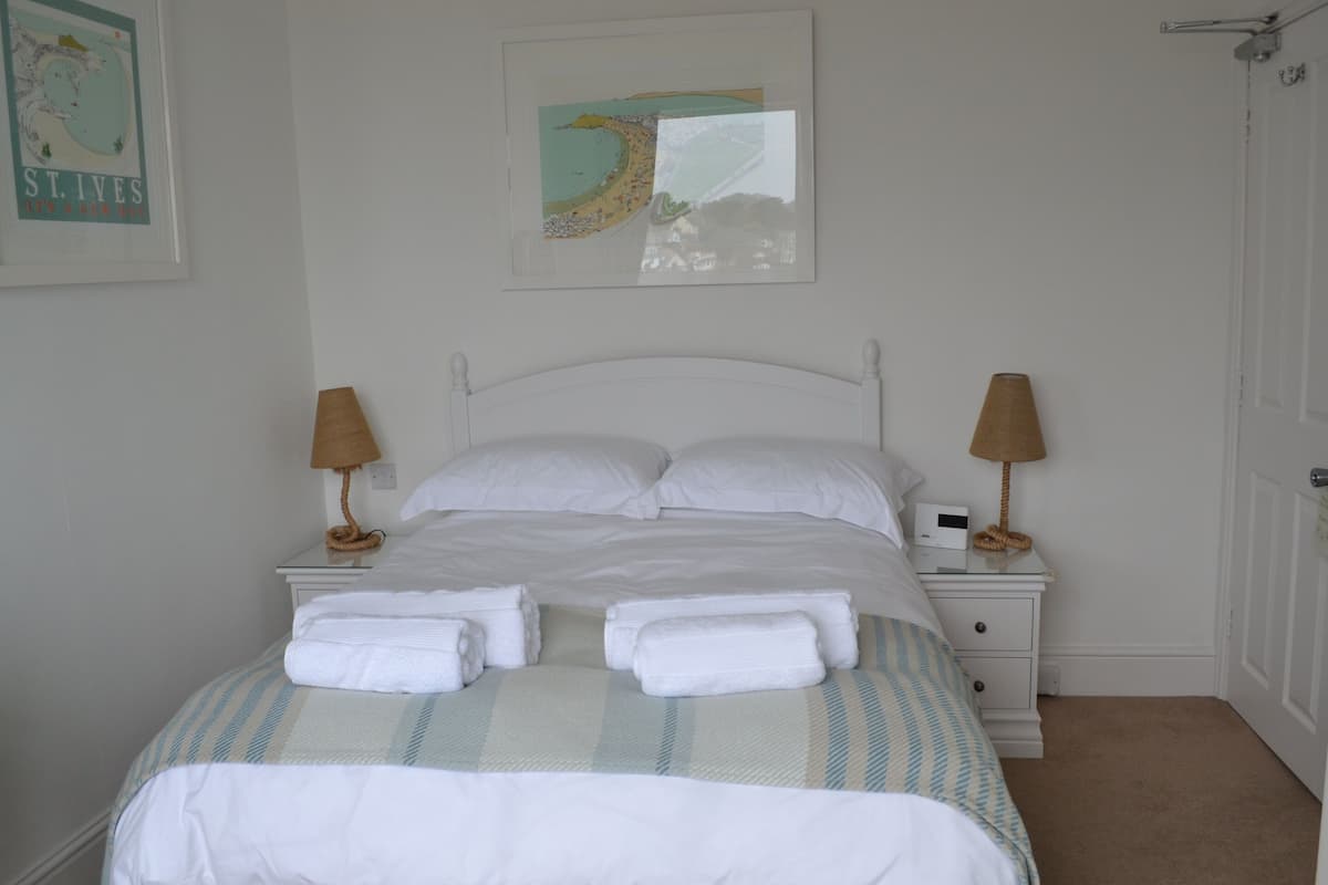 A neatly made bed with white linens and towels, a striped blanket, and two bedside lamps.