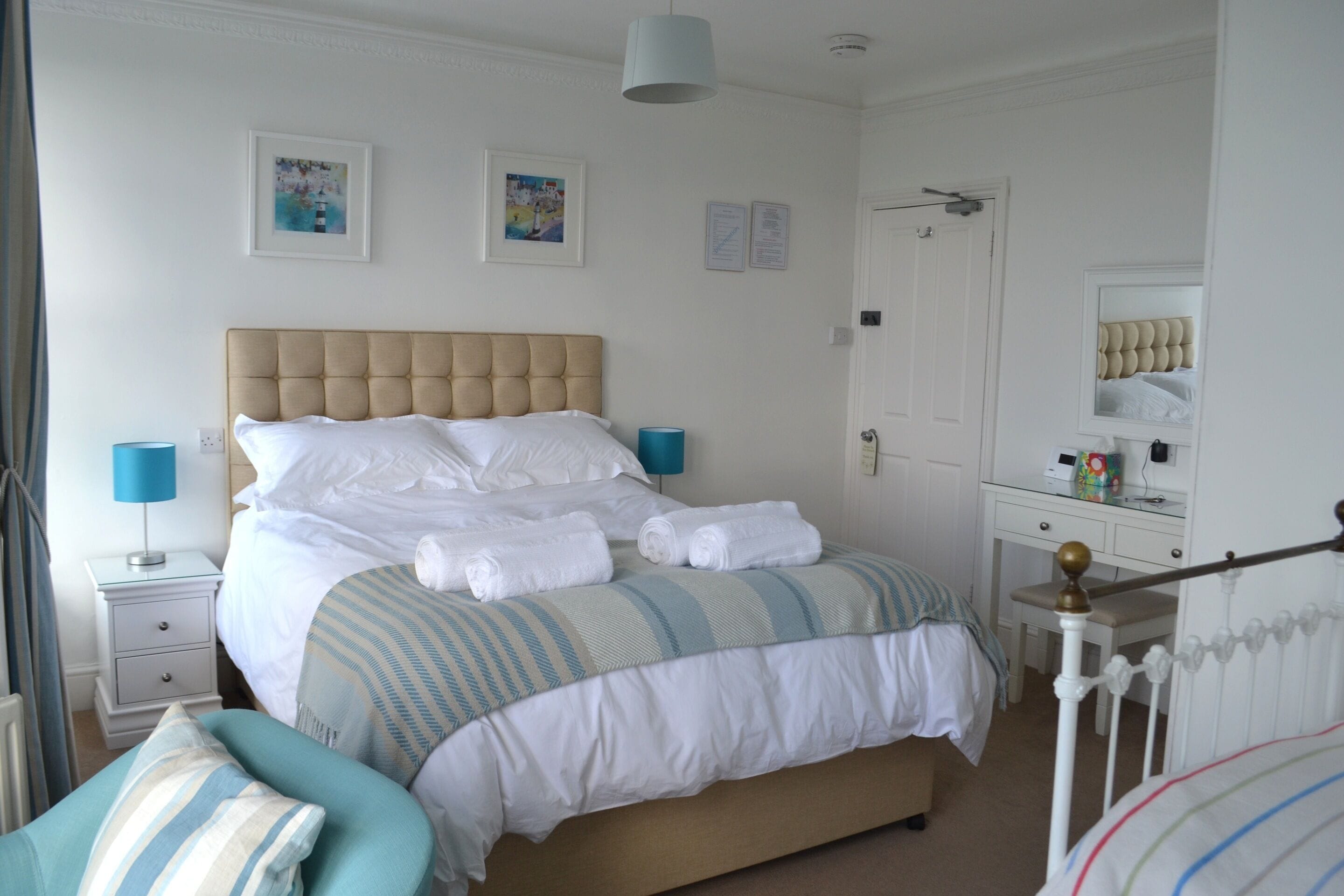 Ein ordentlich eingerichtetes Schlafzimmer mit einem großen Bett, Nachttischen, einer Kommode und einem Spiegel.