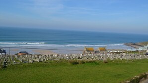 Un cimitero costiero con lapidi, una spiaggia e alcuni edifici sullo sfondo.