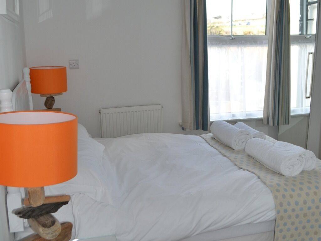 Una camera d'albergo con un letto, una lampada arancione, un termosifone e una finestra con tende.