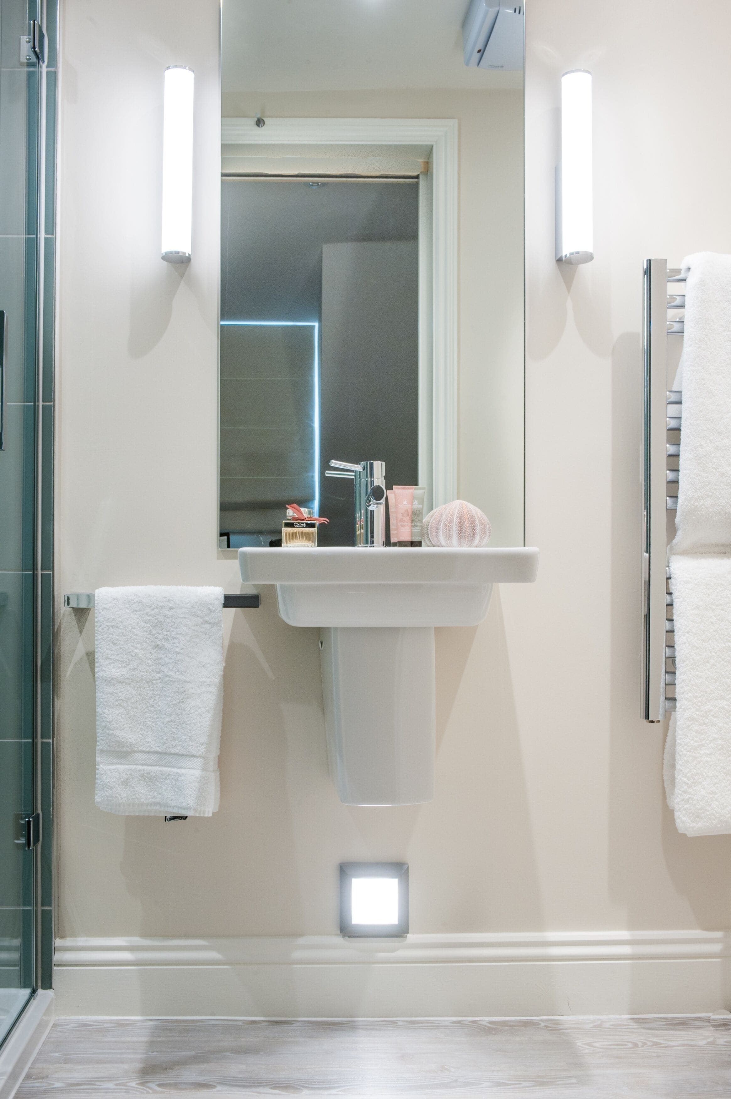 A bathroom with a white sink, a mirror, and a towel rack.