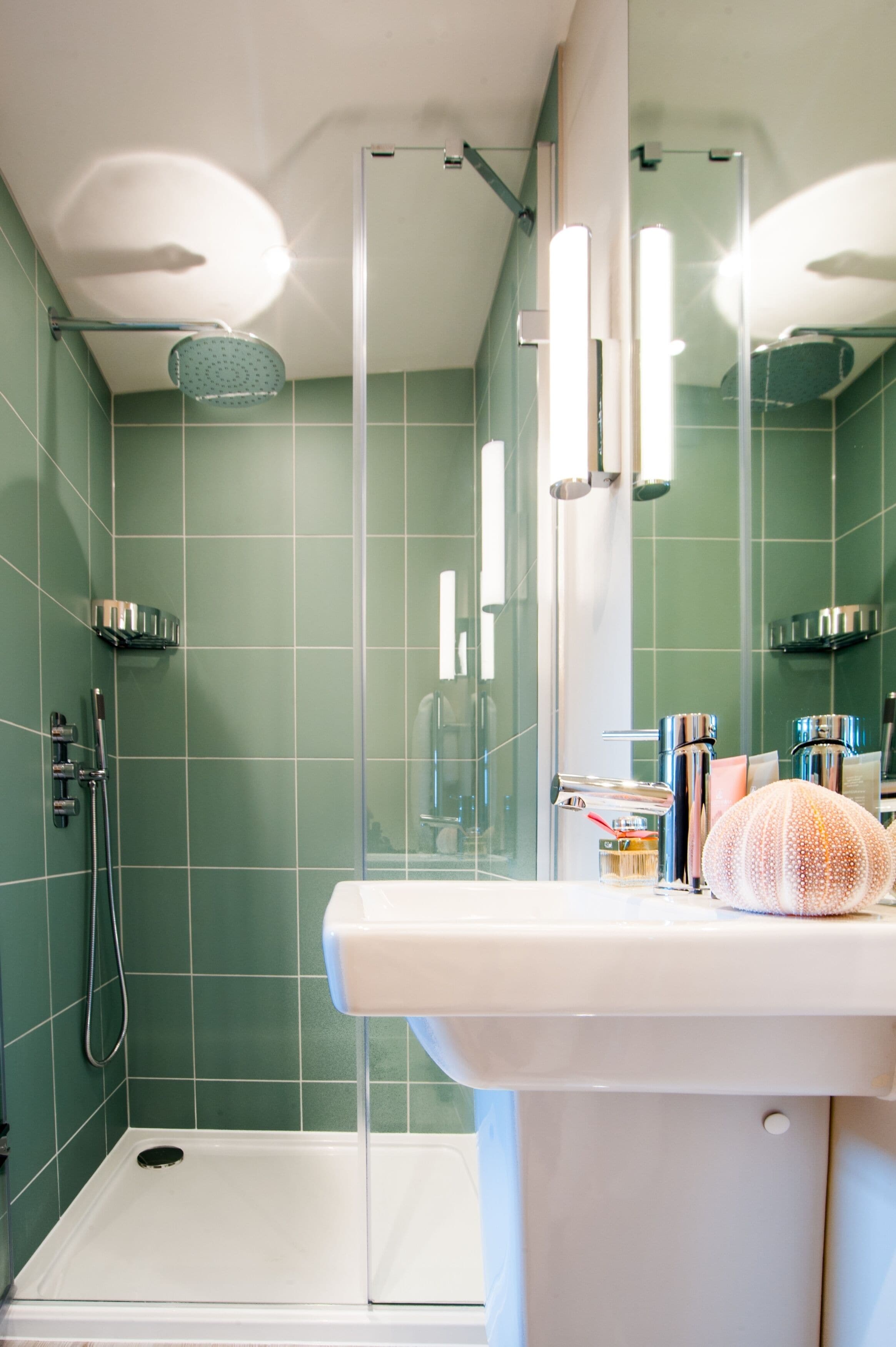 Een badkamer met een douchecabine van glas, een wit wastafelmeubel en een spiegel erboven.