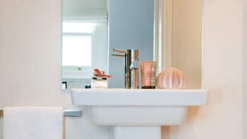 A bathroom with a white sink, a towel hanging on the wall, and a mirror above the sink.