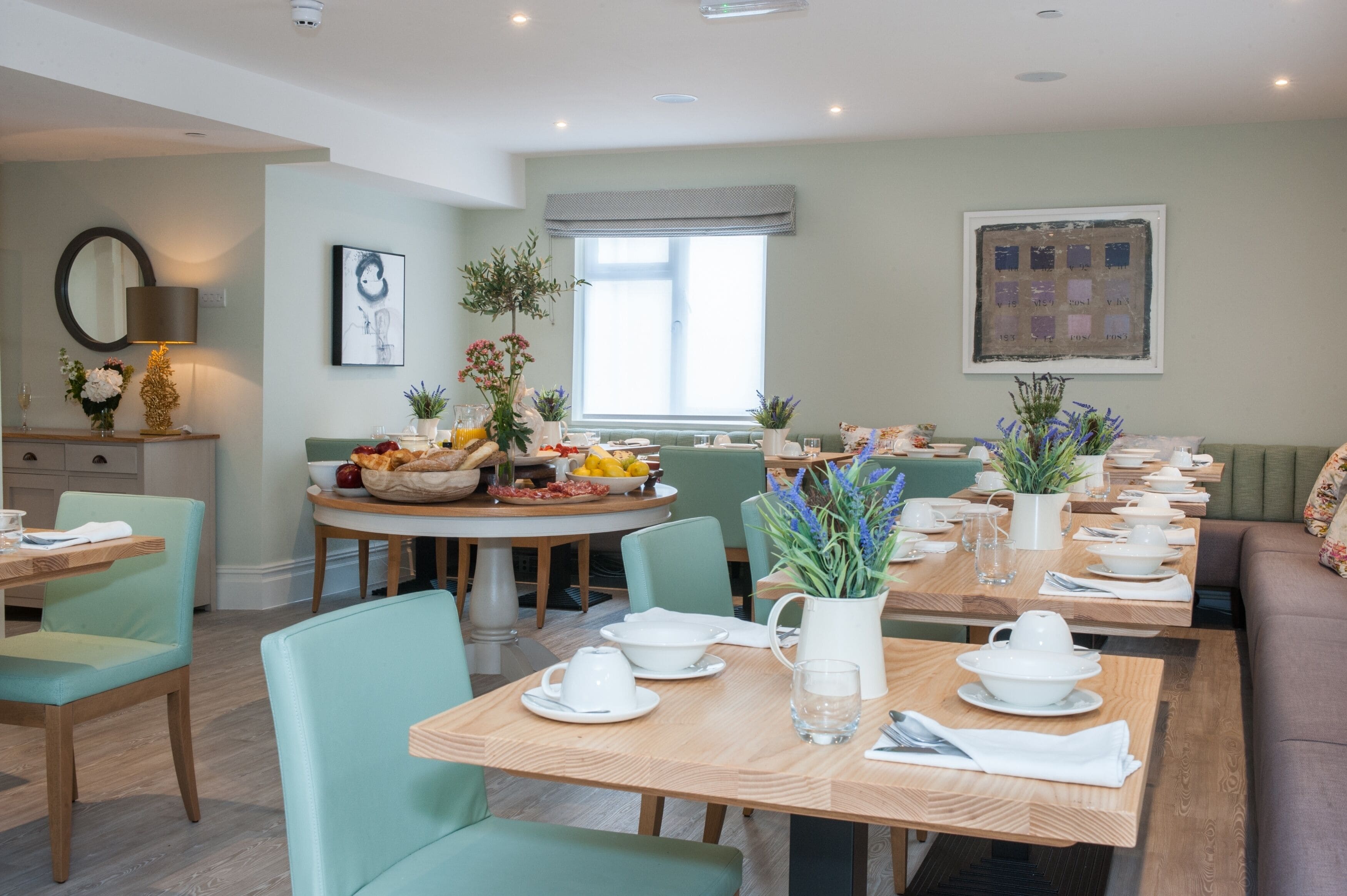 A dining area with multiple tables set for meals, chairs, and a sofa.