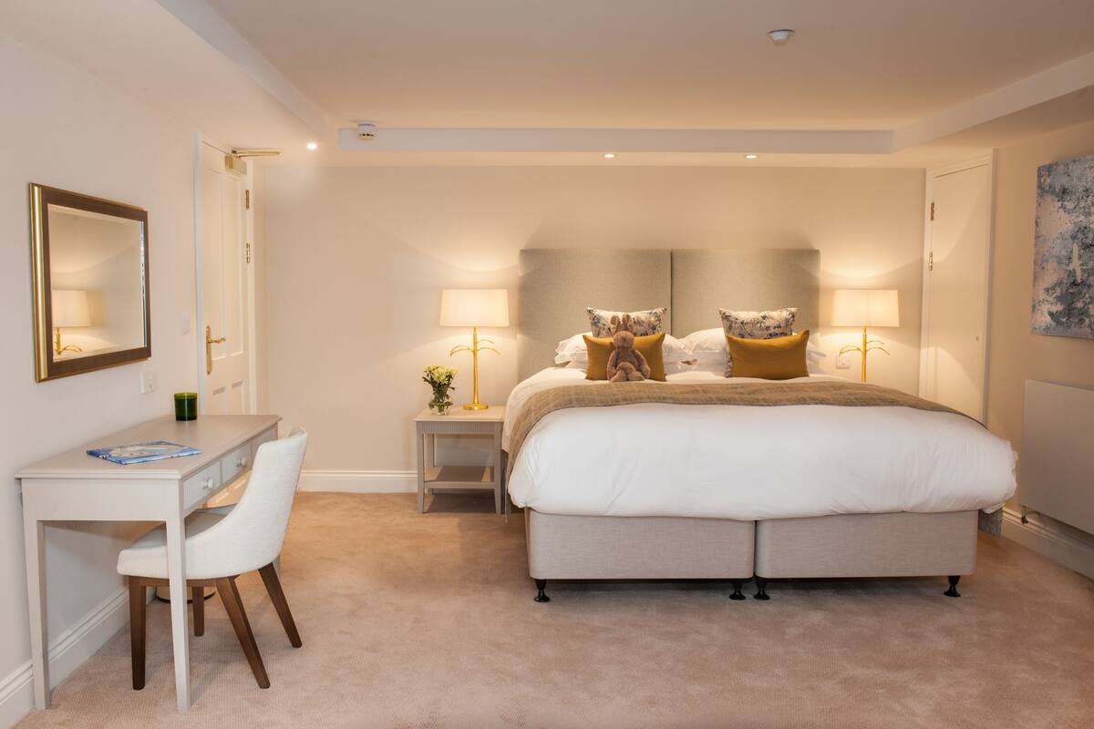 Een slaapkamer met een bed, nachtlampjes, een bureau en een stoel.