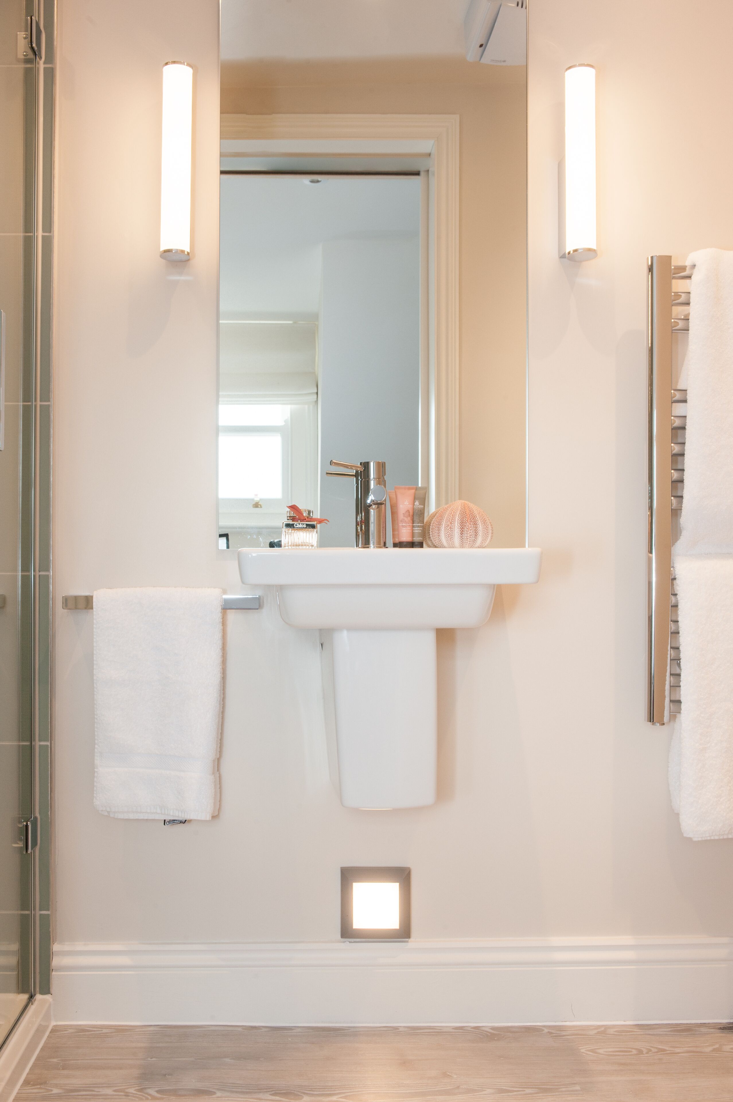 A bathroom with a white sink, a mirror, and two wall-mounted lights.