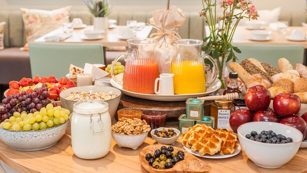 Un bufé de desayuno con diversas frutas, jugos y productos de pastelería.