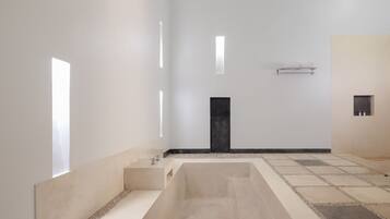 Bathroom features a large bathtub and a small shelf for essentials.