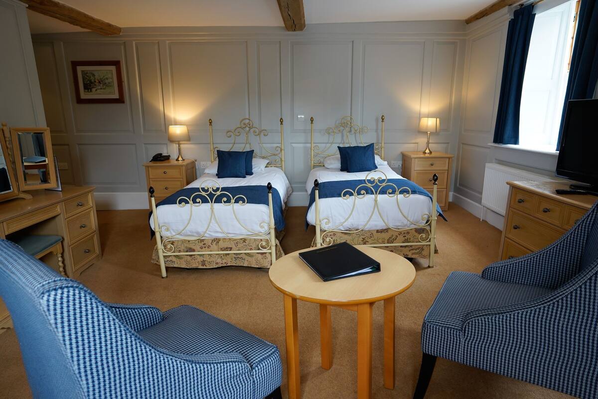 A room with two beds, a desk, a chair, and a TV.