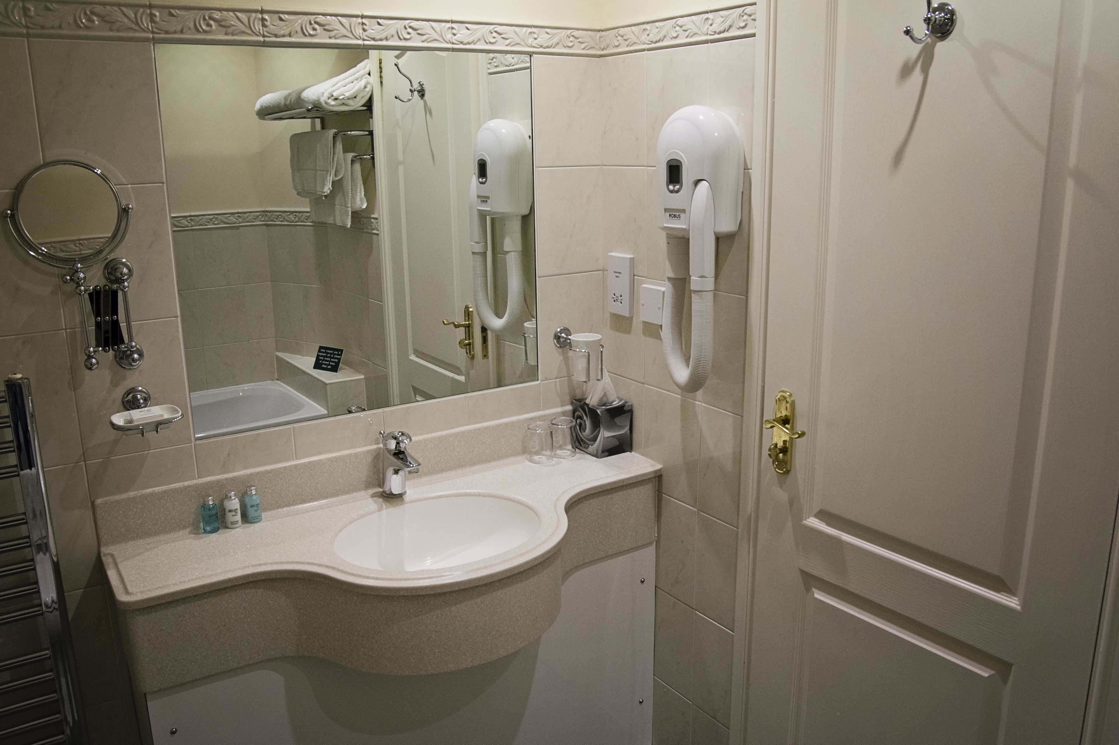Une salle de bain équipée d’un lavabo, d’un miroir, d’un distributeur de serviettes et d’un porte-rouleau de papier toilette.