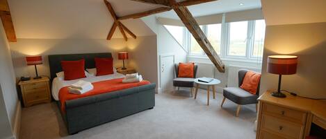 Ein Schlafzimmer mit einem großen Bett, einem Sessel, einem kleinen Tisch und einer Kommode.
