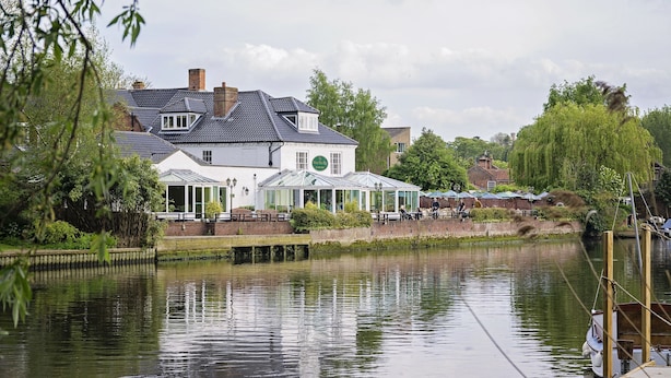 A riverside building with a glass conservatory, a brick facade, and a green sign. - Waveney House Hotel (Beccles)