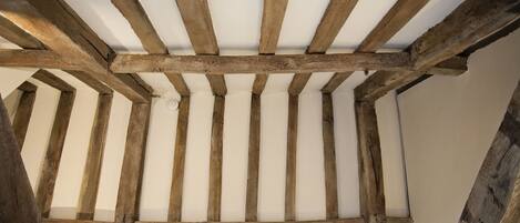 A ceiling with exposed wooden beams and a white wall.