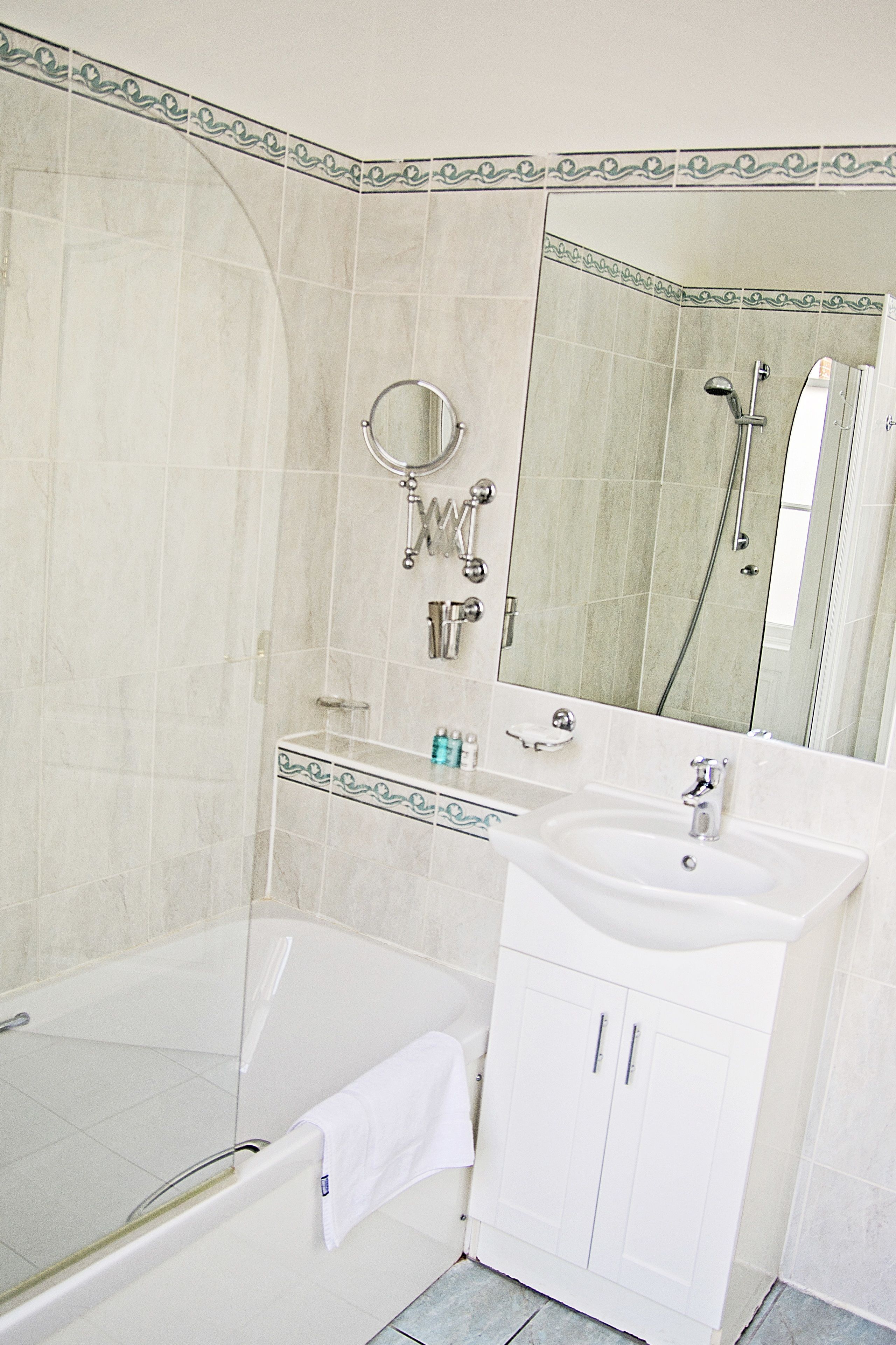 A bathroom with a bathtub, a sink, a mirror, and a shower.