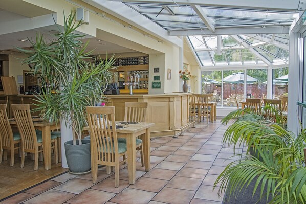 A restaurant with wooden furniture, a bar area, and potted plants.