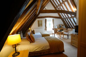 Une chambre avec un plafond en pente, deux lits, un bureau et une chaise.