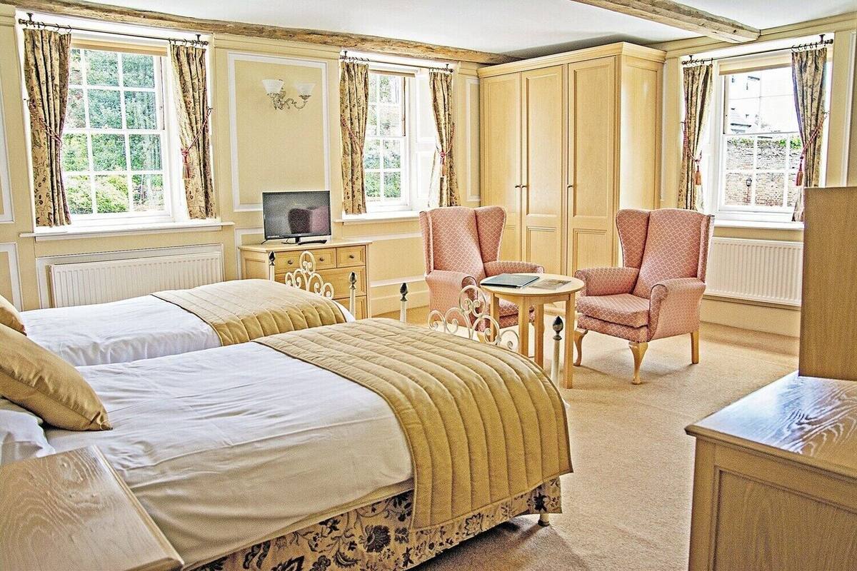 A bedroom with two beds, a television, a small table, and a chair.