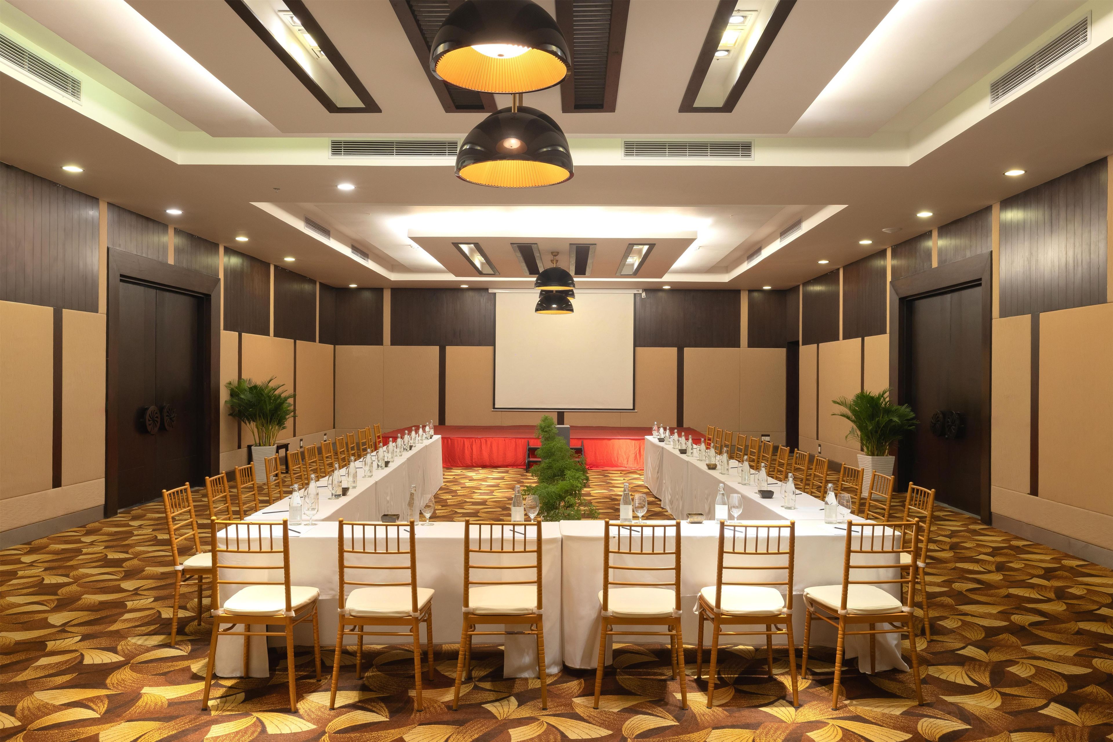 Un salón de conferencias con una mesa larga, sillas y una pantalla para proyector.