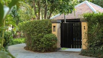 A gated entrance to a building with a tiled roof, surrounded by lush greenery.